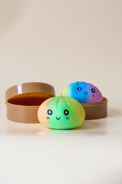 Two colorful dumpling shaped squishy toys with smiling faces in plastic steamer baskets