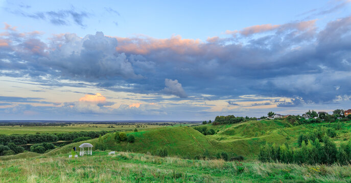 Vast meadow under colorful evening sky with grazing sheep