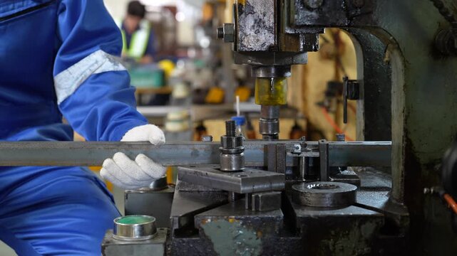 Industrial worker operating metal press machine in workshop, gloved hand shaping steel component for precision manufacturing and mechanical production with factory machinery and heavy equipment