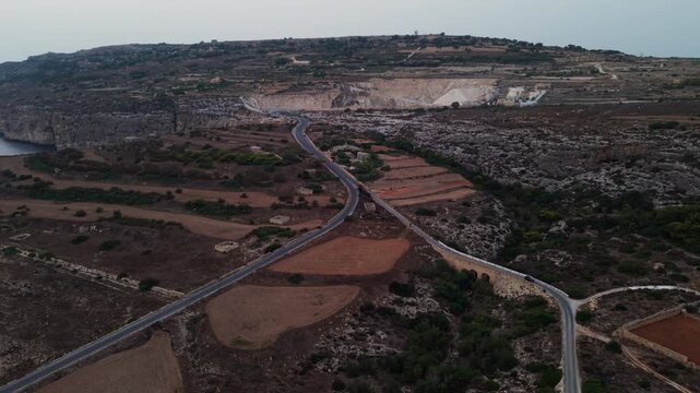 Aerial drone shot of Ghar Lapsi Road in Siggiewi Malta during Sunset capturing the dramatic coastline and limestone quarries.