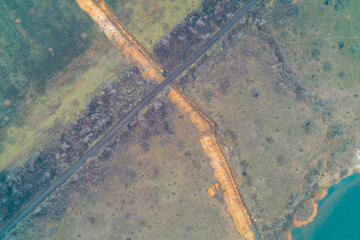 Obraz premium Earthworks and anti tank ditch line constructed along reservoir shoreline, high angle top view aerial drone shot