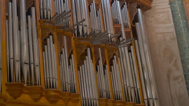 Majestic pipe organ inside historic cathedral. Magnificent and ancient pipe organ with its large silver pipes inside an old cathedral, a beautiful musical instrument for classical and liturgical music