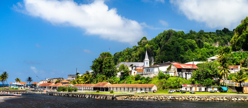 Panoramic scenic view of the coastal village of Grand Riviere with its historic church, colorful houses, lush green hills, and waterfront in Martinique, Caribbean.