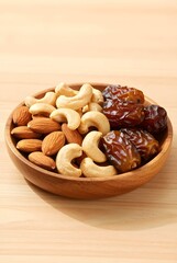 Fototapeta premium Wooden Bowl Filled with Assorted Dates, Almonds, Cashews, and Healthy Snacks