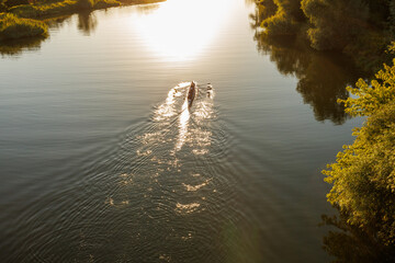 Aerial view of rowing crew boat on calm river at sunrise © Iryna Miadzvedzeva