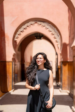 Young woman smiling while exploring the historic Bahia Palace in Marrakech enjoying the intricate architecture and rich cultural heritage of Morocco experiencing travel and discovery