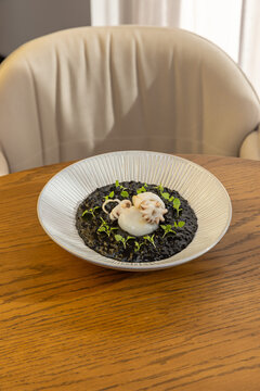 Black squid ink risotto served with small tender cuttlefish in a bowl