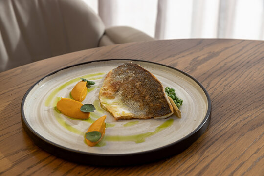 Pan seared fish fillet with carrot puree green peas and herb oil