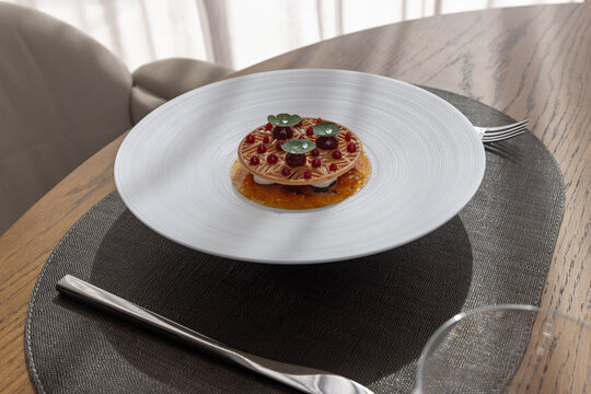 Gourmet modern dessert served on a wide white rim plate at a luxury restaurant table