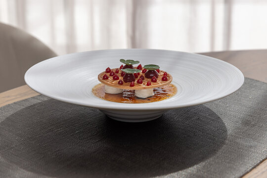 Elegant fine dining dessert served on a white deep rim plate in a modern setting