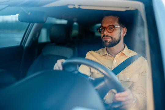 Young man driving car wearing eyeglasses and seatbelt