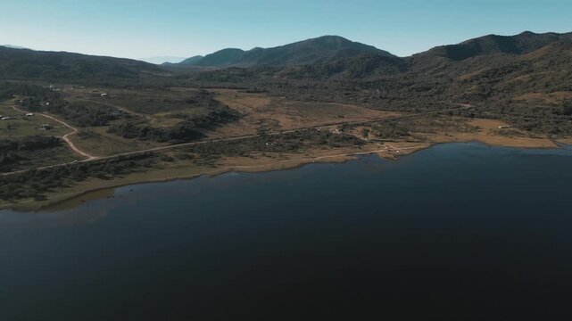 Aerial view of a still reservoir winding beneath dusk toned mountain ridges