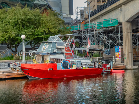 Ottawa, Ontario, Canada. Sep 9, 2026. Red custom boat docked along Rideau Canal near Plaza Bridge construction and National Arts Centre.