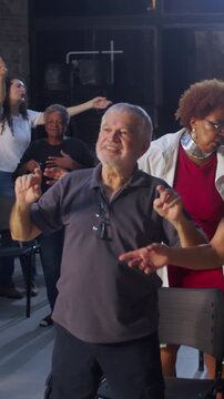 Diverse evangelical congregation dancing in sync, turning around, and worshiping together with joyful praise in modern church sanctuary
