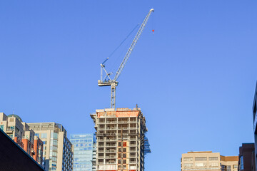 Construction crane towering over city buildings under blue sky © kodai
