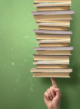 Hand Carefully Balancing a Huge Heavy Stack of Educational Books