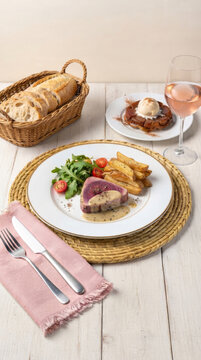 Grilled tuna with a creamy peppercorn butter sauce, rustic fries, fresh salad, artisan bread, a glass of ros&eacute; wine, and tarte Tatin with vanilla ice cream
