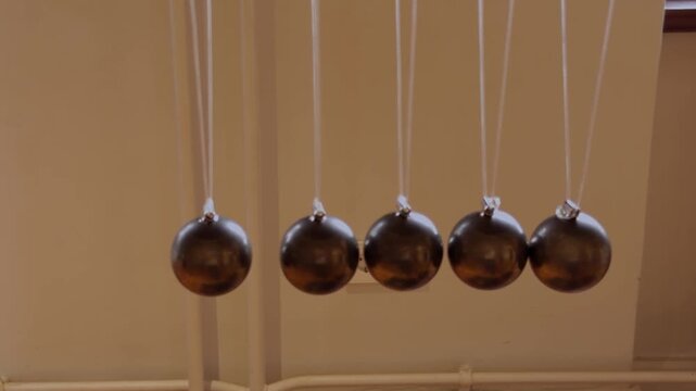 Newton's cradle with suspended metal balls demonstrating momentum, collision and conservation of energy.