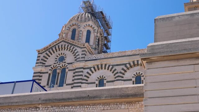 Ornate altar and richly decorated apse inside Notre-Dame de la Garde Basilica in Marseille, France. Golden mosaics, colorful religious artwork and a statue of the Virgin Mary highlight the sanctuary