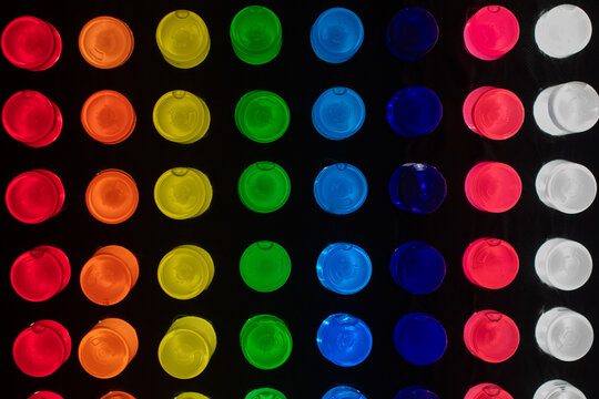 A black light box with a black background and rows of colorful lite pegs. The rows of pegs include blue, white, red, blue, green, yellow, orange, and red. The pegs are round plastic tubes.