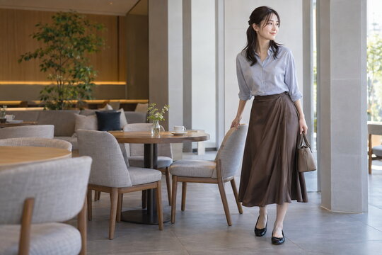 明るいカフェで椅子を引くシャツ姿の女性