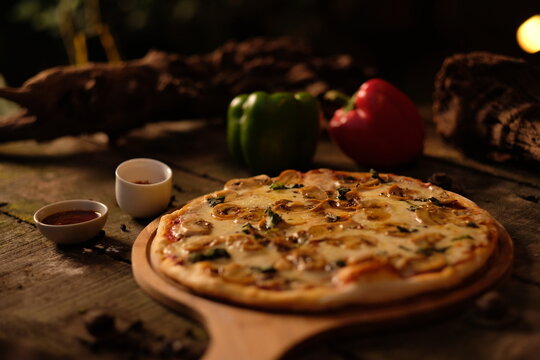 Freshly baked mushroom pizza with melted cheese served on a rustic wooden board with bell peppers
