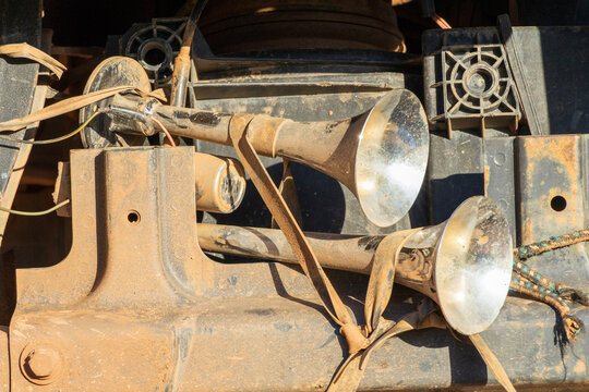 Semi-truck chrome air horn fastened using rubber straps with a sparkle of sunlight