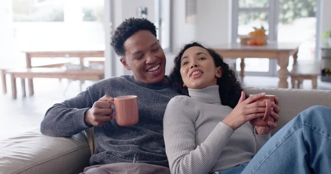 Couple sitting on living-room couch holding matching mugs, woman telling story, man listening