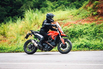Dynamic Motorcycle Rider on Open Road Surrounded by Greenery © j_chaikom
