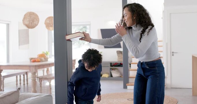 Mother at home placing hardcover book on son's head against post to record height
