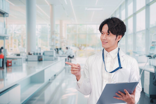 白衣を着て研究室で研究をする男性の研究員