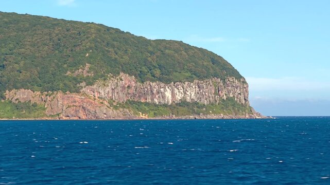 航行する船から断崖の岬を望む風景。