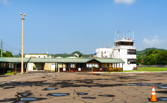 View across the tarmac toward the terminal building and air traffic control tower at George F. L. Charles Airport in Castries, Saint Lucia under a clear blue sky.