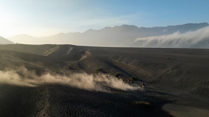Tenggerese horse riders crossing the volcanic landscape around Mount Bromo in East Java, Indonesia, surrounded by drifting volcanic sand and dust. © huong