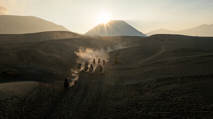 Tenggerese horse riders crossing the volcanic landscape around Mount Bromo in East Java, Indonesia, surrounded by drifting volcanic sand and dust. © huong