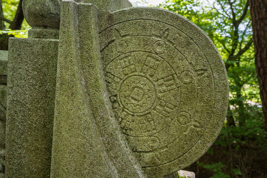 A Buddhist wheel of dharma is delicately carved into a mossy stone bridge balustrade at a traditional Korean temple entrance.