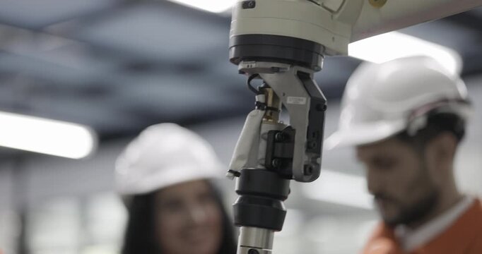 Female and Male engineers checking or maintenance electronic in AI or artificial intelligence robot arm in the manufacturing automation and robotics manufacture room. Service technical engineer.