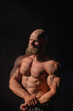 A male bodybuilder in shorts poses showing off his muscles.
