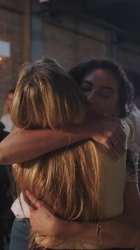 Two young female Christian parishioners warmly embracing each other inside a church sanctuary conveying holy love, sacred fellowship, and emotional support

