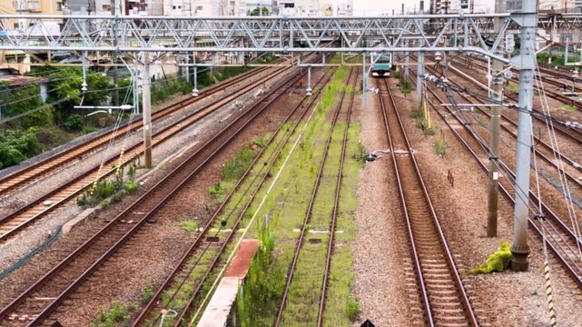 Keihin-Tohoku Line commuter train approaching through a broad multi-track railway corridor near Tsurumi, Yokohama