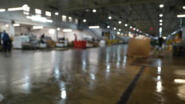 Stock footage of a worker walking through a busy industrial warehouse filled with packaged goods and logistics materials, representing supply chain operations.
