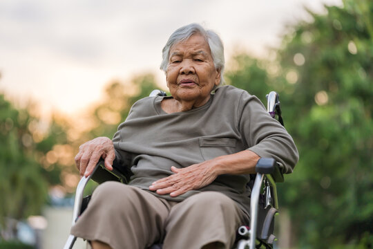 senior woman suffering from stomach ache while sitting in wheelchair at park