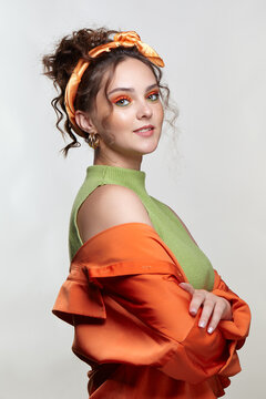 Young woman on gray background with green eyes makeup and curly hair with hairband.
