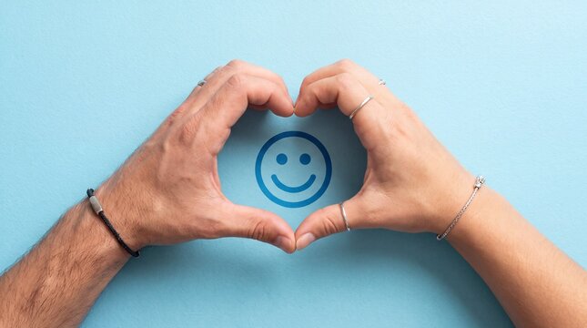 Two hands making a heart shape around a happy face icon on blue background for positive feedback and customer satisfaction concept