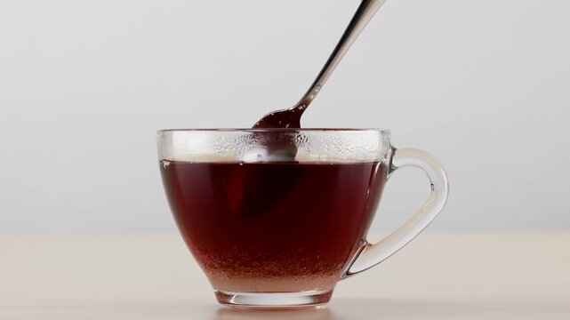 Adding Sugar and Stirring Black Tea in Glass Cup
