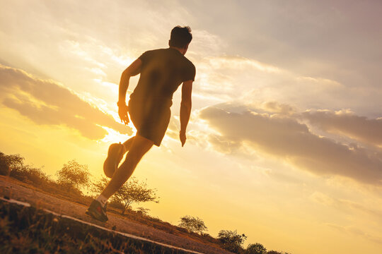 Silhouette of young man running sprinting on road. Fit runner fitness runner during outdoor workout with sunset background. selected focus
