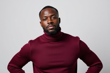 Obraz premium Confident man in maroon turtleneck posing with hands on hips against white wall