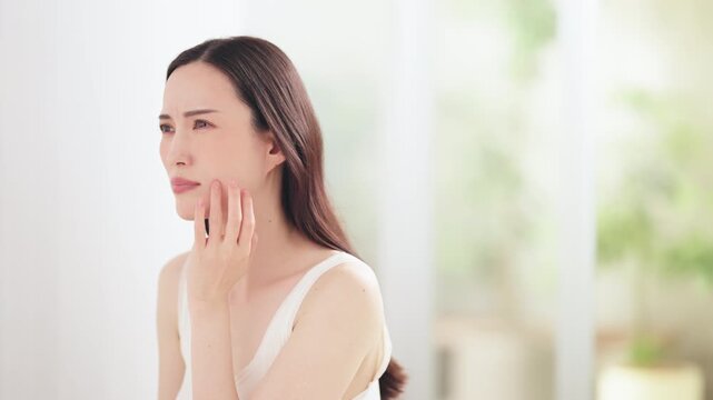 鏡を見て肌を気にする日本人女性