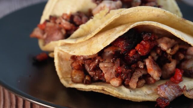 Tacos with charred meat and red chorizo on black plate