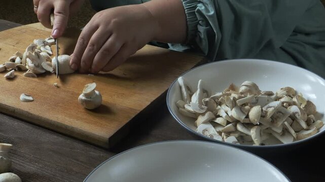 Cutting fresh champignons with a knife on a cutting board